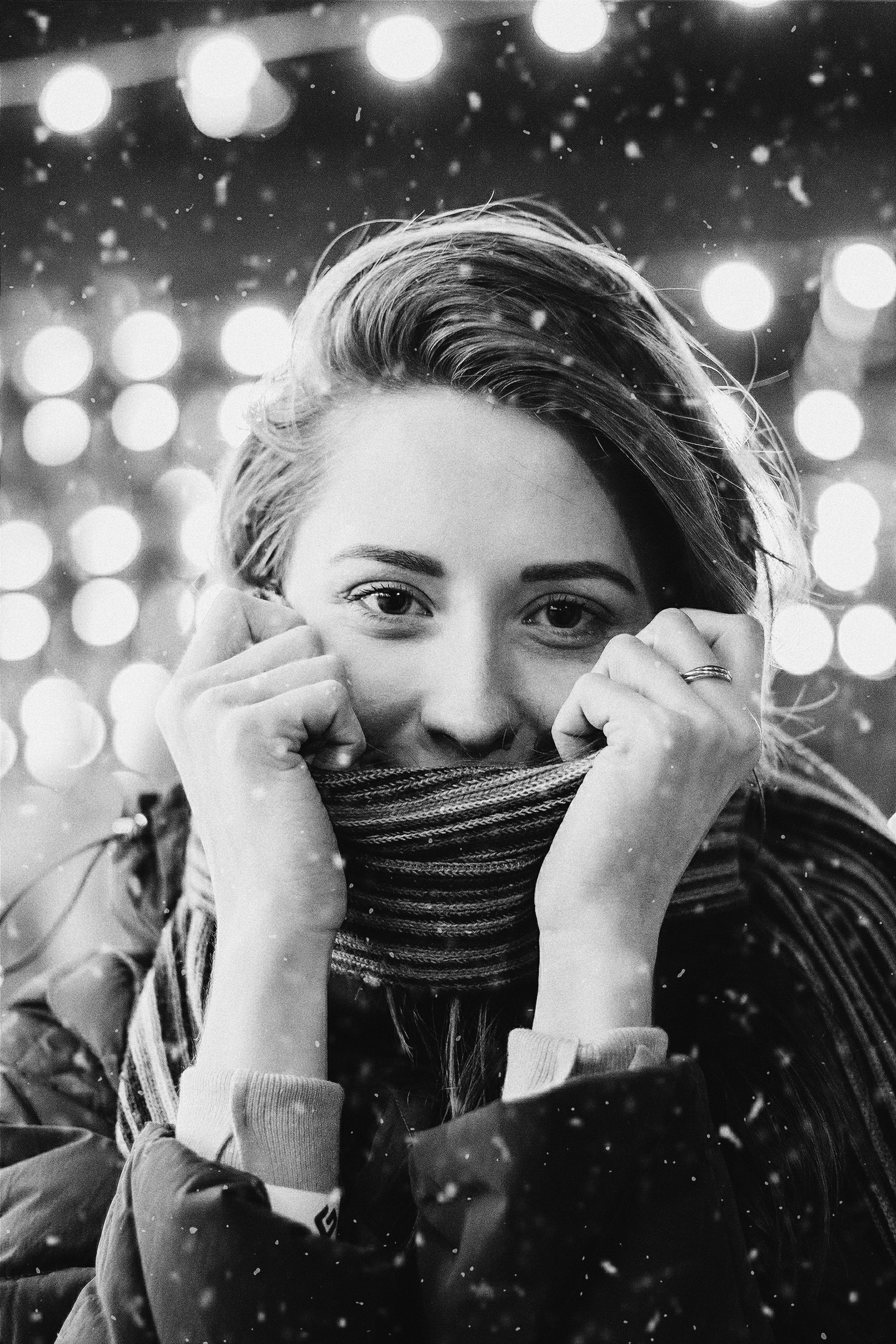 Cheerful black and white portrait of a woman in winter attire, warmly wrapped in a scarf.