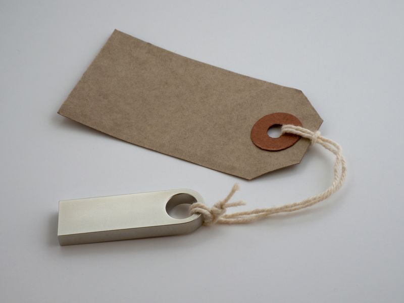 Blank brown paper price tag tied with twine on a plain background