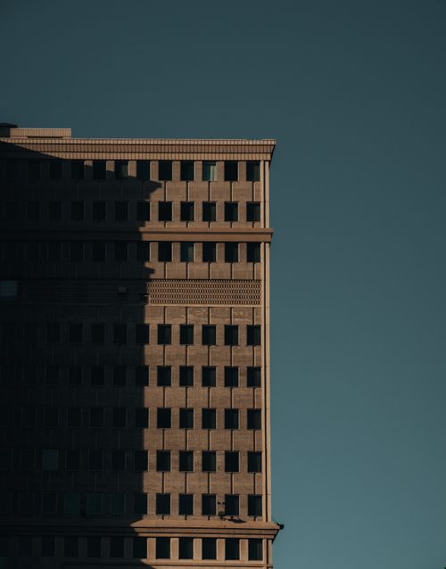 Free A towering skyscraper captured with a clear sky background showcasing architectural details and shadows. Stock Photo