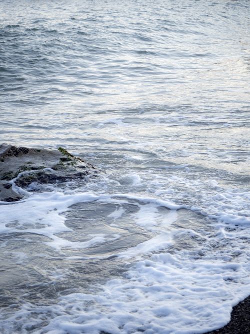 Free Tranquil view of gentle ocean waves crashing onto a rocky shoreline, showcasing the beauty of nature. Stock Photo