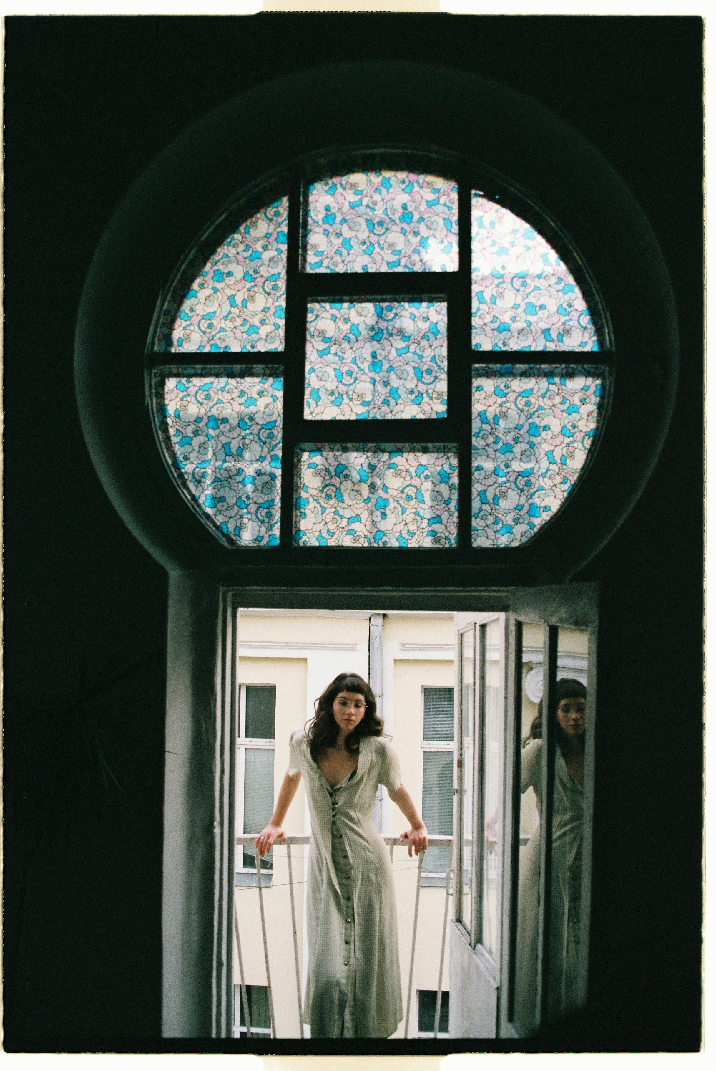 Elegant woman in a window frame, posing on a balcony in Moscow. Historic and artistic element.