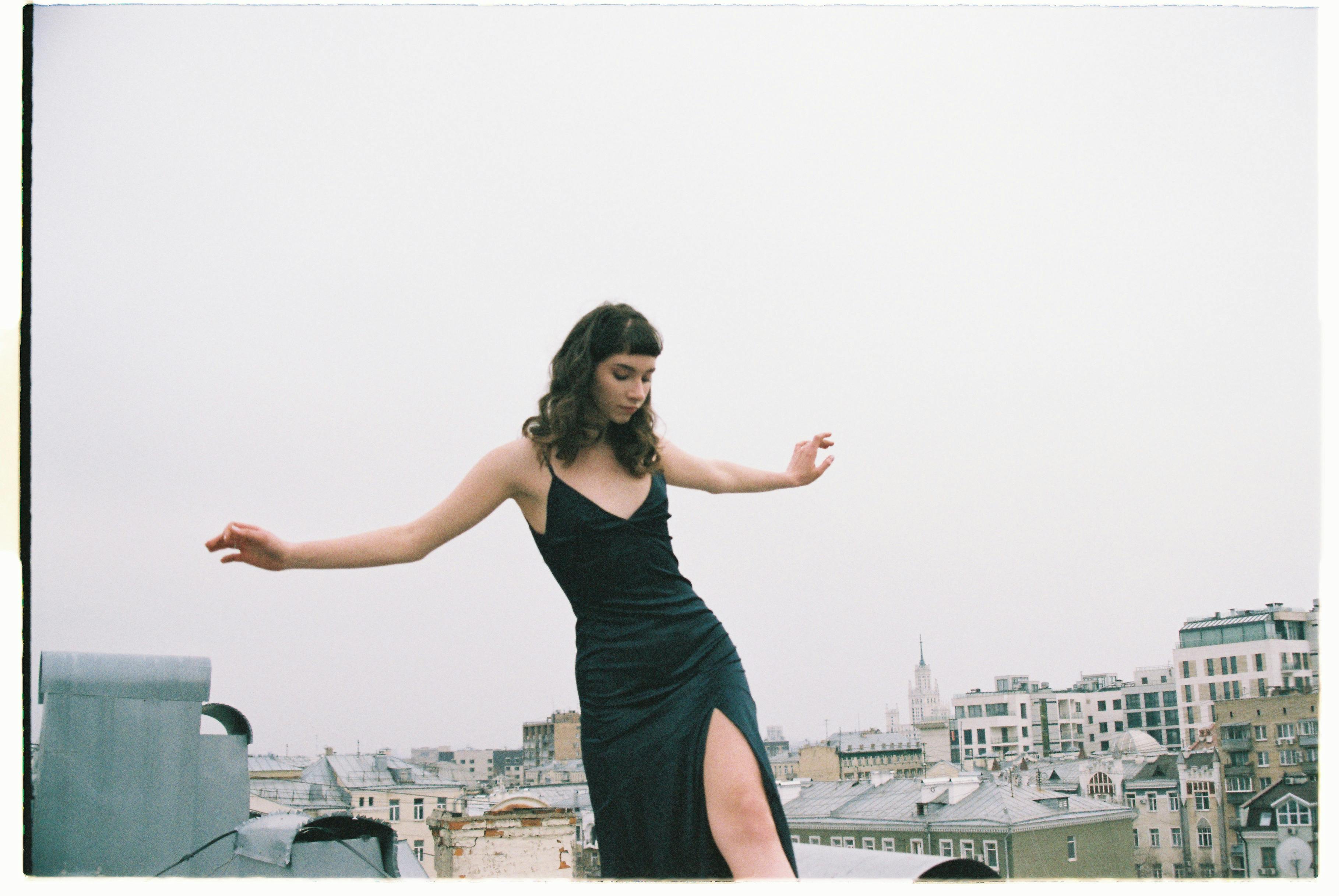 Stylish woman posing on a Moscow rooftop, cityscape view in the background.