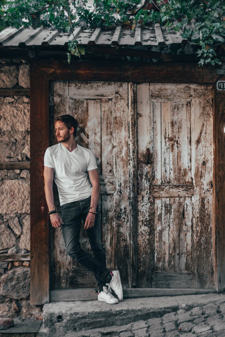 A Man In A White Shirt Leaning On A Door