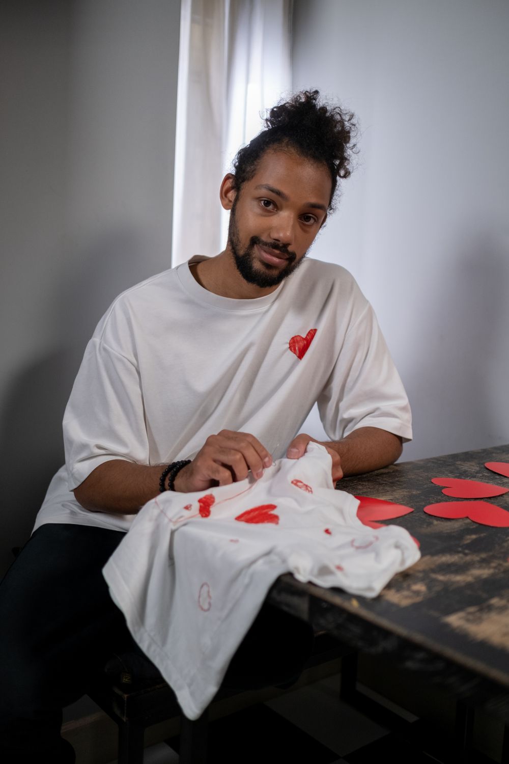 A member of the studio in a white tee with a hand-stitched red heart