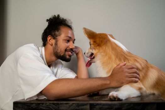 Man and corgi sharing a joyful moment indoors, showcasing self love and companionship.