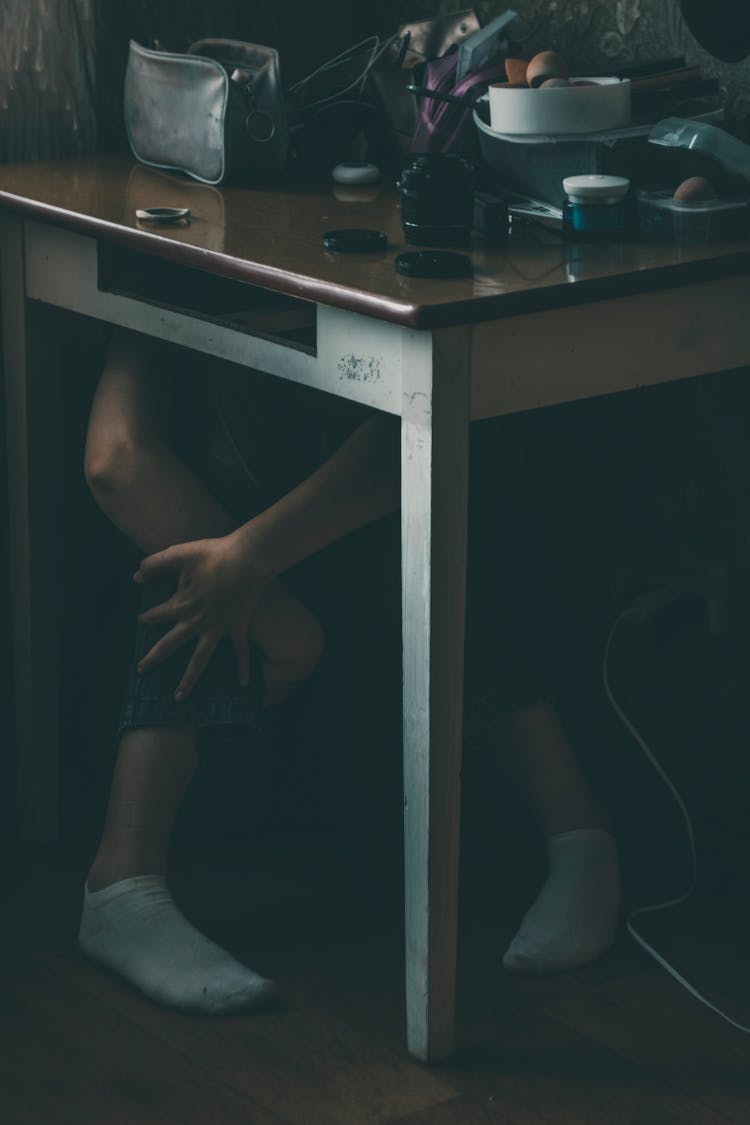 Person In White Socks Sitting Under The Table