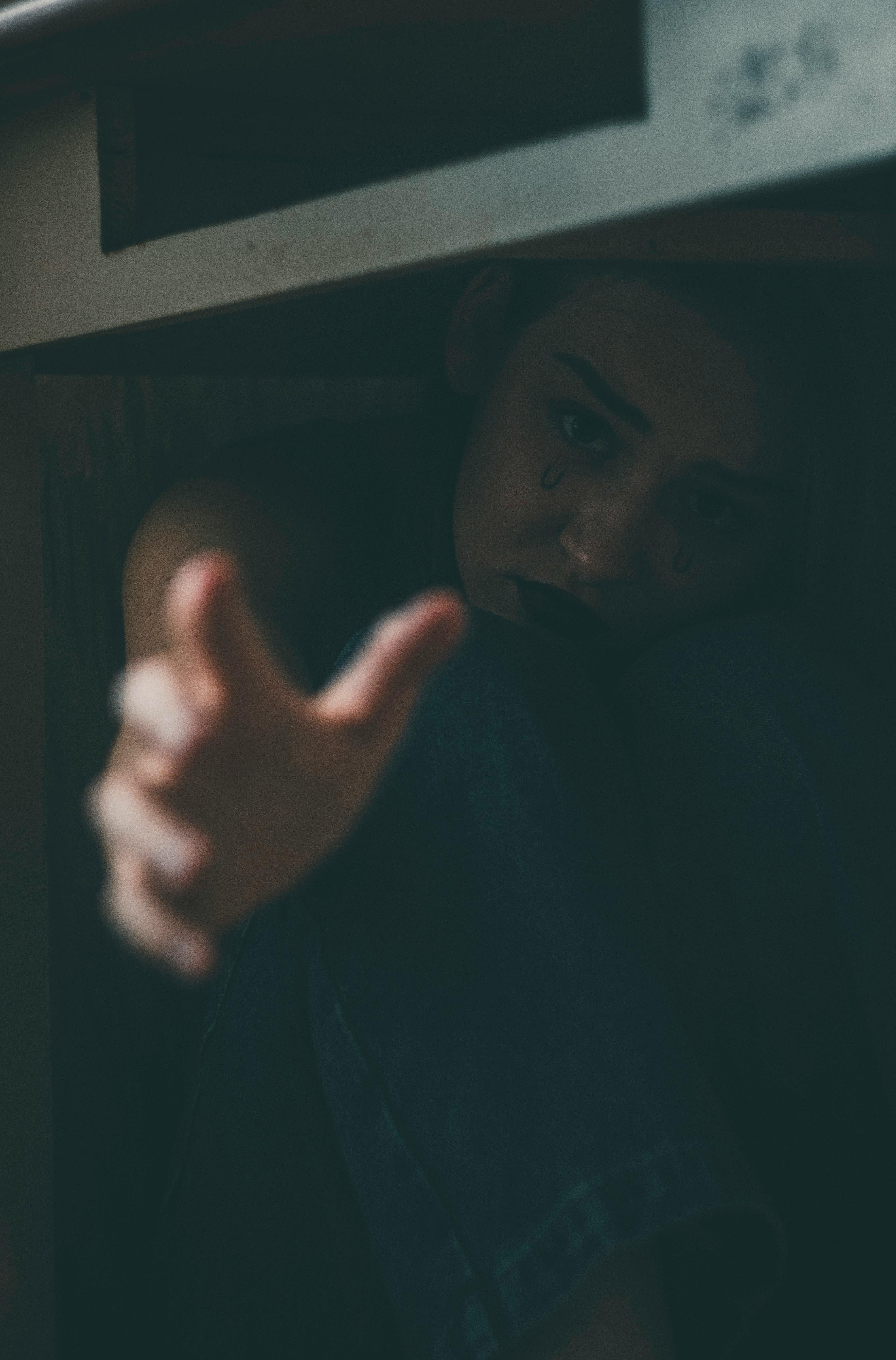 Woman Crouching Under a Table with Hand Reaching Out · Free Stock Photo