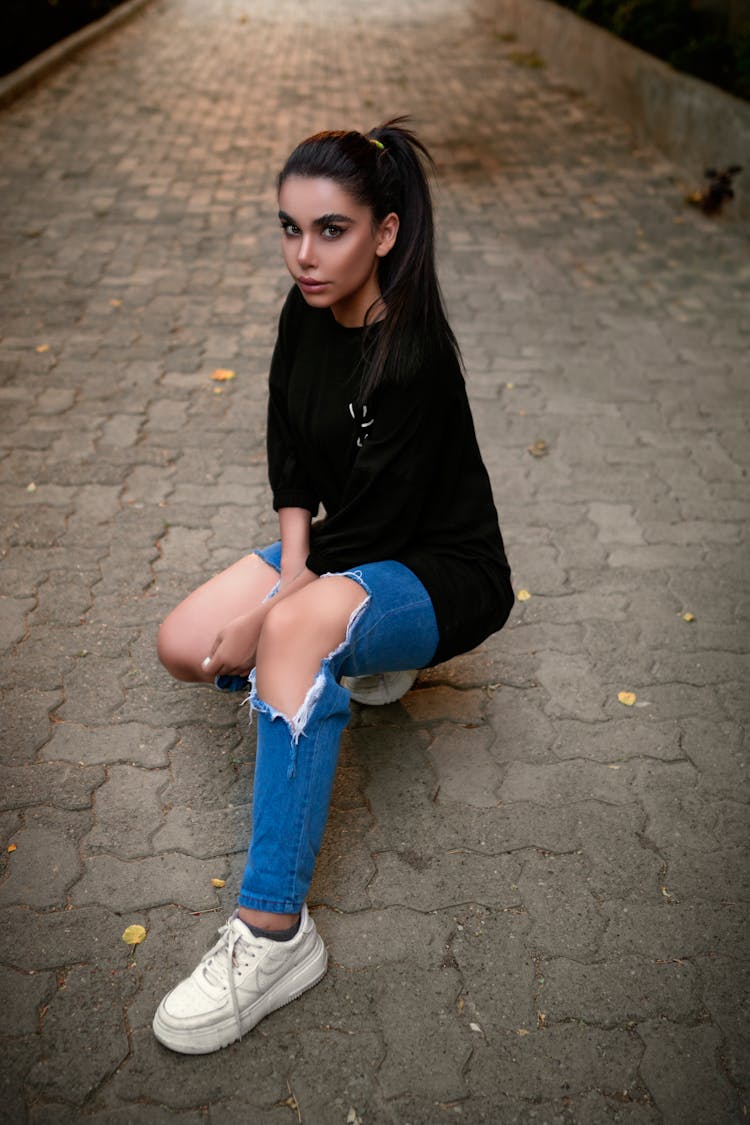 A Woman In Black Shirt Crouching On Brick Floor