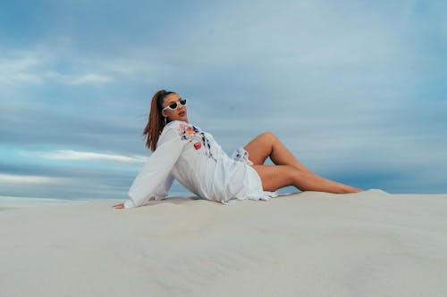 Woman in White Long Sleeve Dress Sitting on Sand