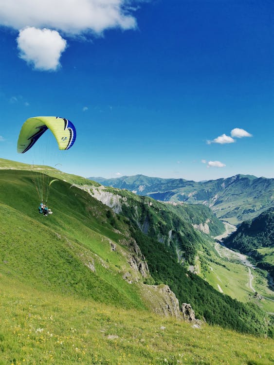Yellow parachute over green mountains