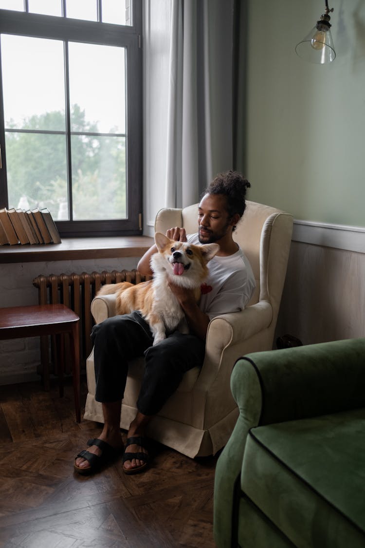 Man Sitting With Dog On Armchair