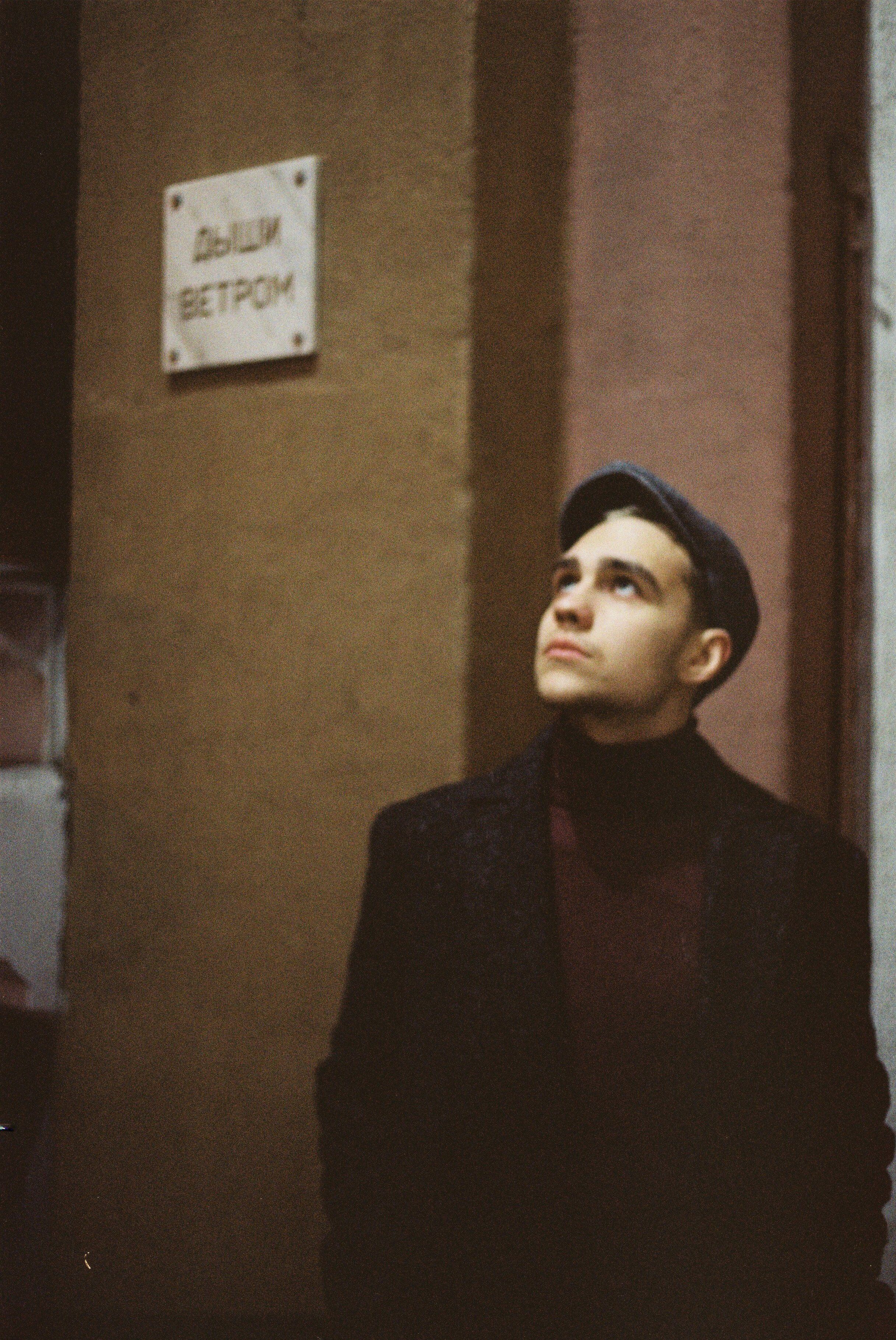 A man gazing upwards in an urban setting with a vintage aesthetic.