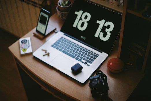 A cozy home workspace with a laptop, smartphone, camera, and headphones. Ideal for tech enthusiasts.