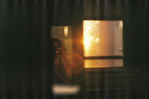 Free A blurred reflection of a person with sunset through a window creating a warm glow. Stock Photo