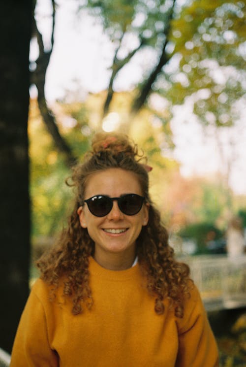 A Female Smiling and Wearing a Sunglasses in a Park 