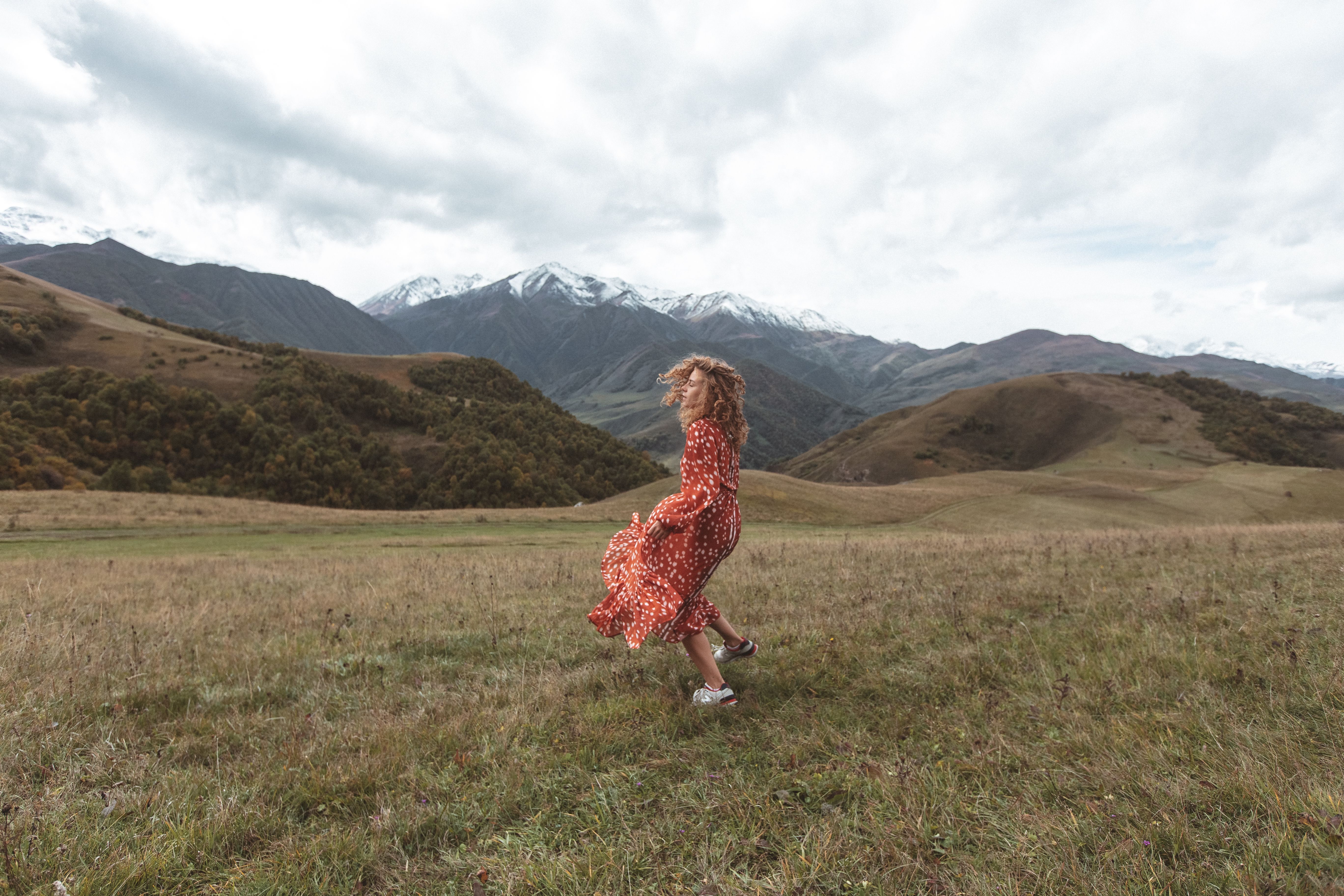 A Woman in Red Dress Standing on a Grassy Field · Free Stock Photo