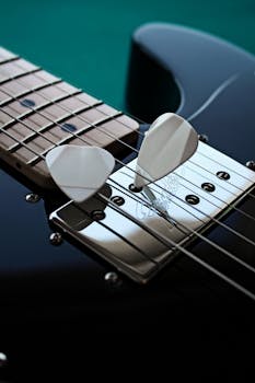 Detailed image of a glossy electric guitar with picks on the strings.