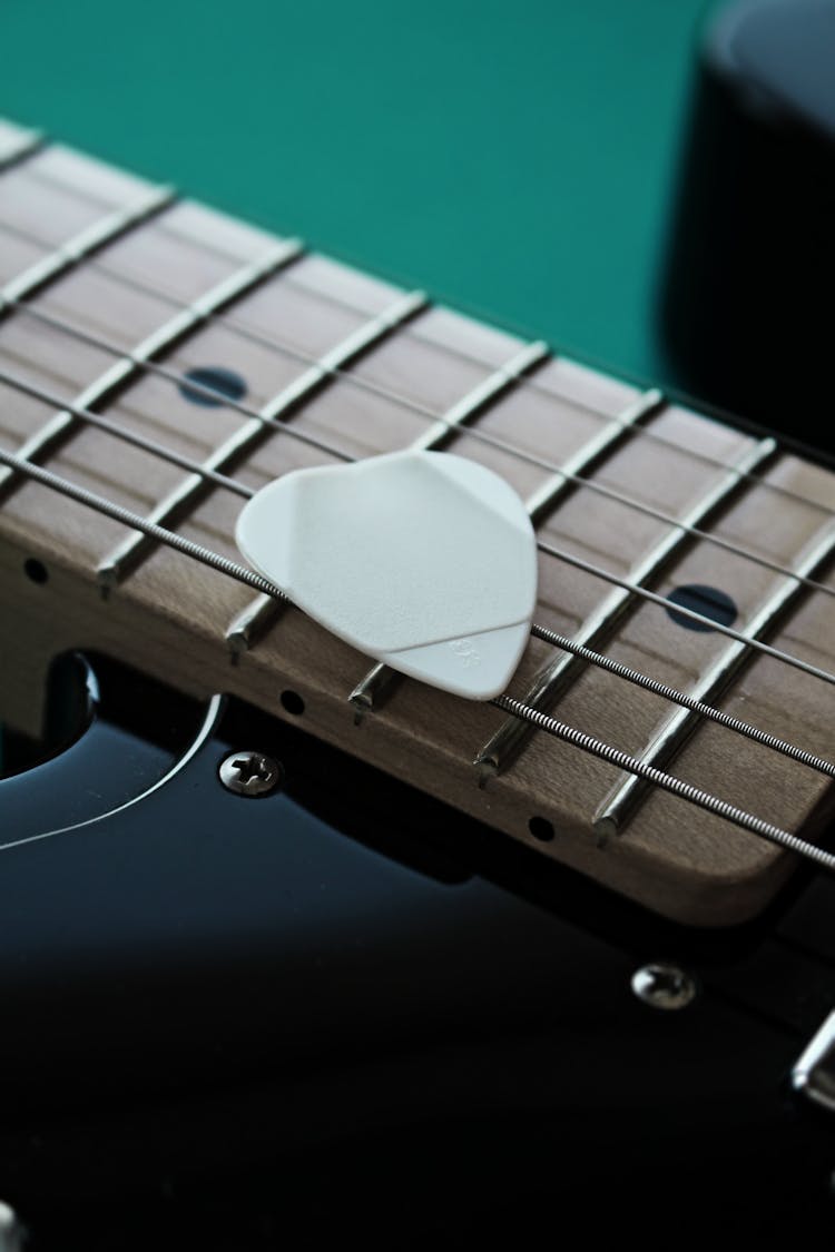 Guitar Pick Laying On Black High Gloss Electric Guitar 