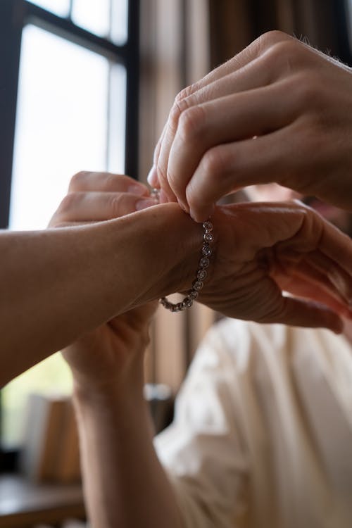 Free Man Putting Gifted Bracelet on Hand of Woman Stock Photo