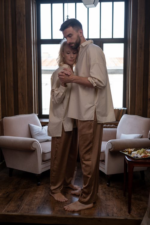 Free Couple Wearing Pajamas Dancing Near a Window Stock Photo