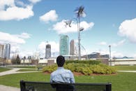 在不列颠哥伦比亚省萨里的一张长凳上，一个人正坐着观察城市天际线和独特的公共艺术