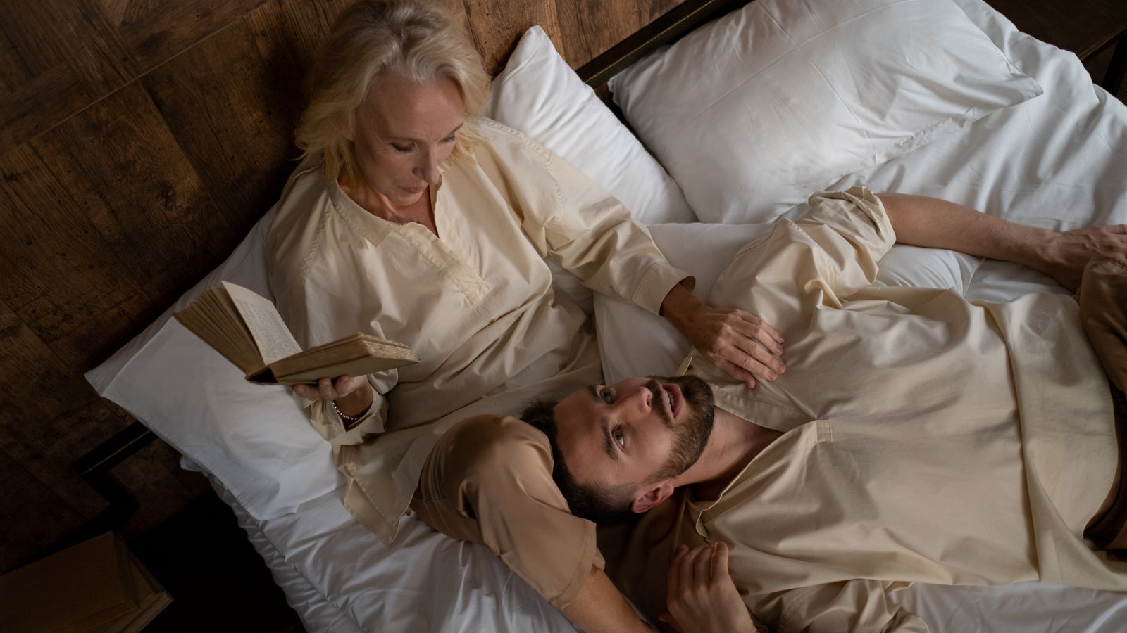 A couple lying in bed, a little distant