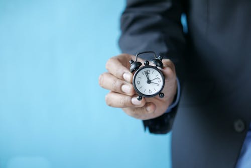 Person Holding Black and White Analogue Clock