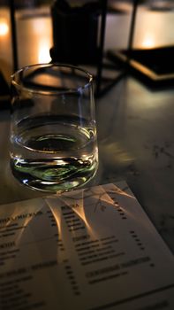 A glass of water on a dimly lit table with reflections casting a serene mood.