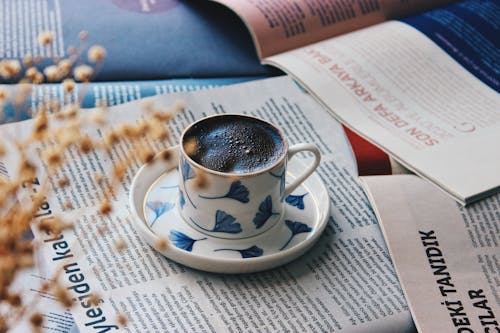 Free Cup of Coffee on Top of a Magazine Stock Photo