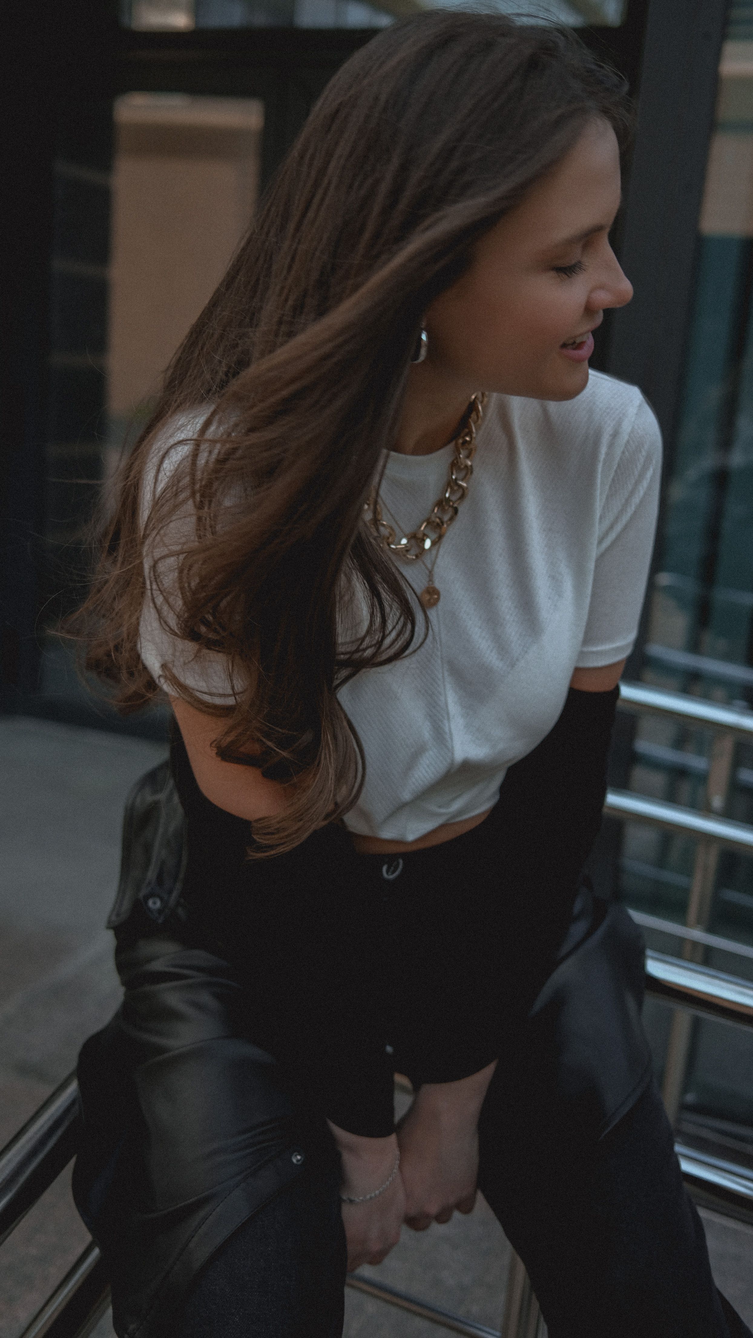 Fashionable woman in outdoor urban setting with a warm, muted tone.