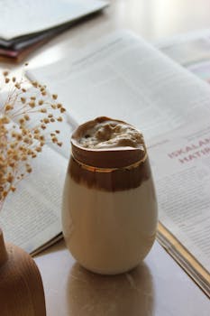 Latte with foam on table beside an open magazine, cozy and inviting.