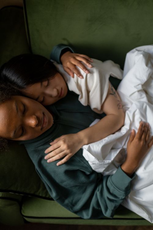 Free A serene, intimate moment showing a sleeping interracial couple embracing indoors. Stock Photo