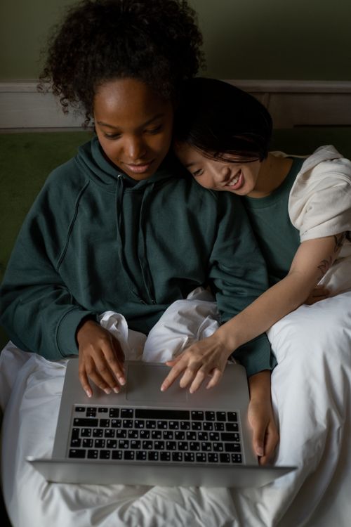 Free A loving interracial couple enjoys a cozy moment indoors, sharing a laptop together. Stock Photo