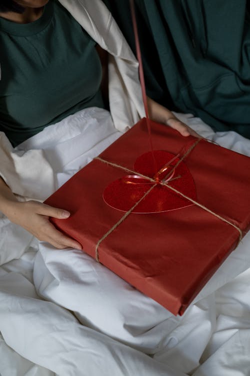 A Person in Green Shirt Holding Red Gift Box