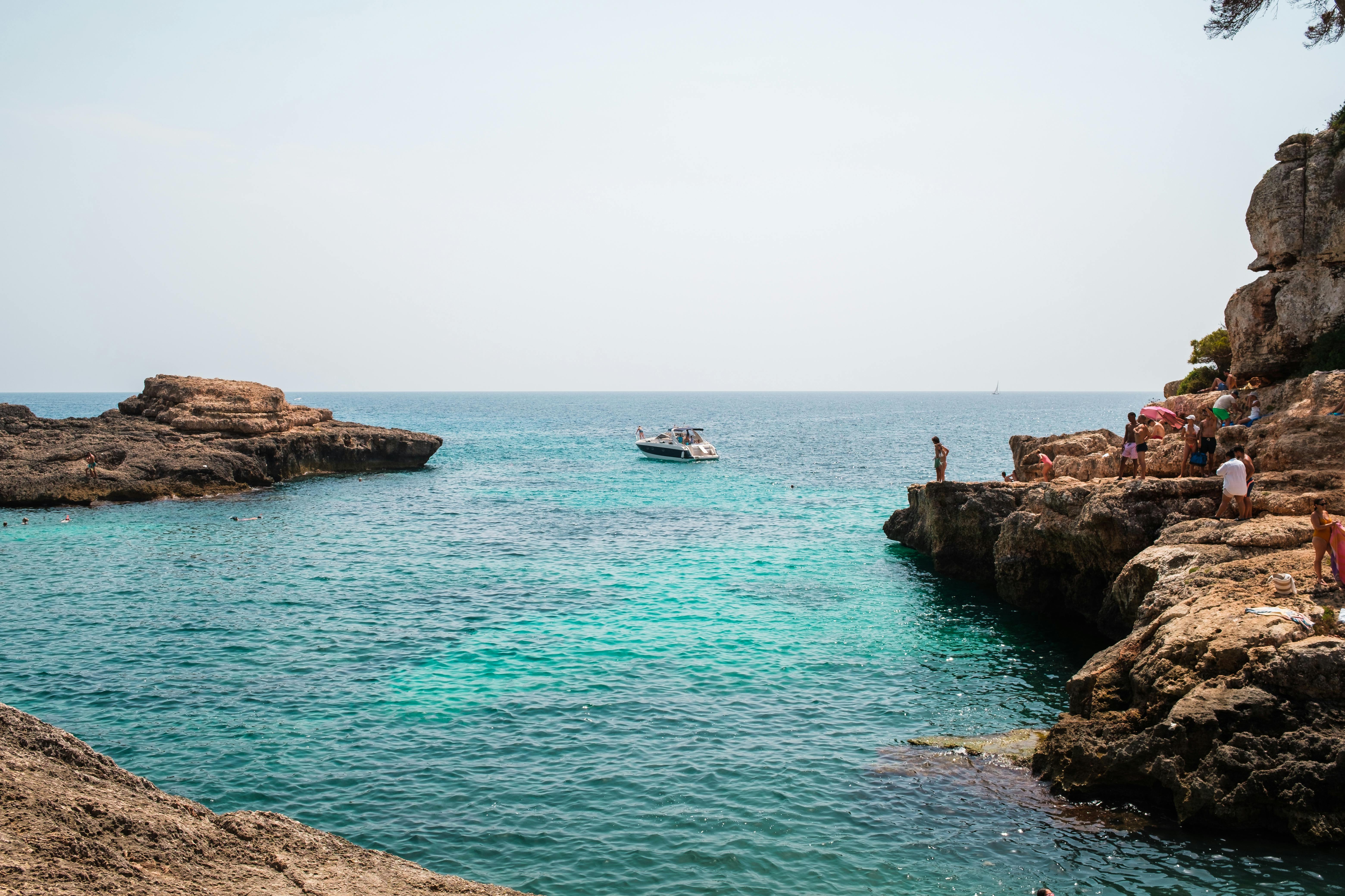 游客在海边享受夏日时光，乘坐摩托艇在岩石附近巡航