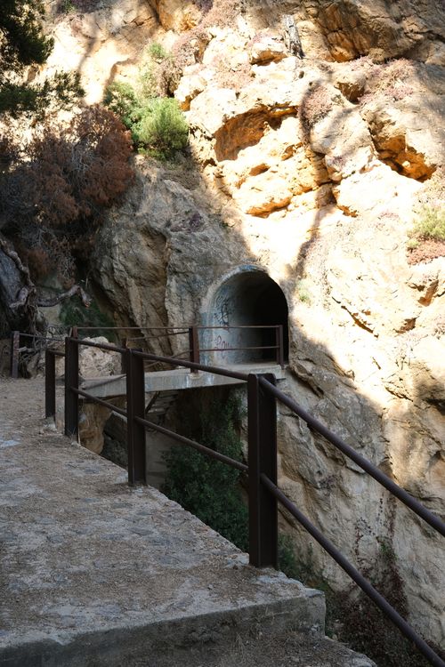 Free Tunnel entrance on rocky cliff path with sunlight and shadows. Stock Photo