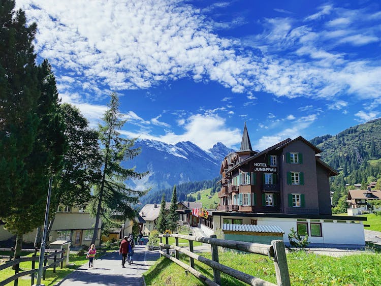 People Walking In Front Of The Hotel With A Mountain View