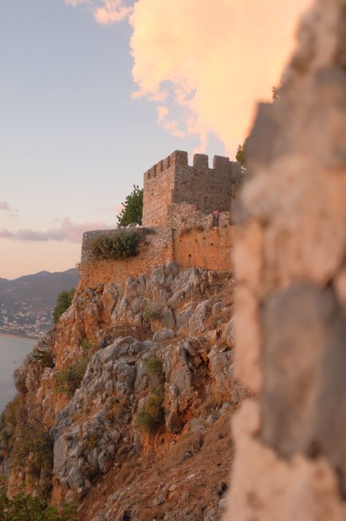 Free Ancient castle ruins on a rocky cliff with a scenic ocean view at sunset. Stock Photo