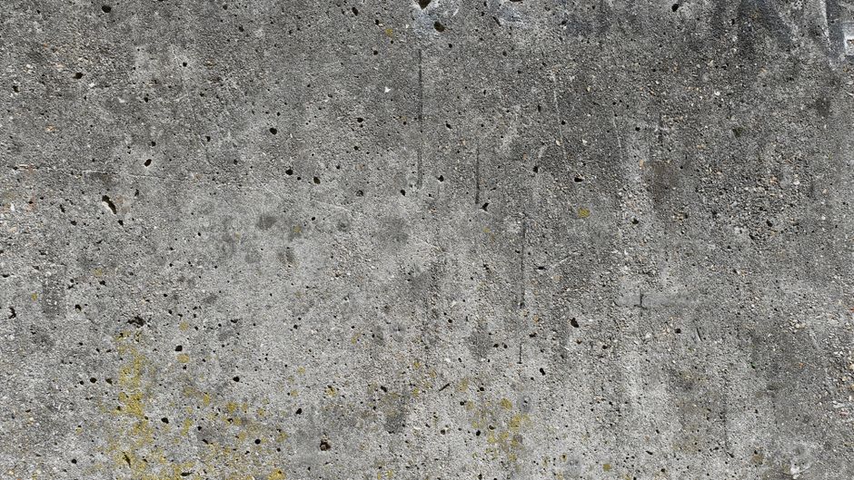 Close-up of a grungy concrete wall surface featuring stains and holes.