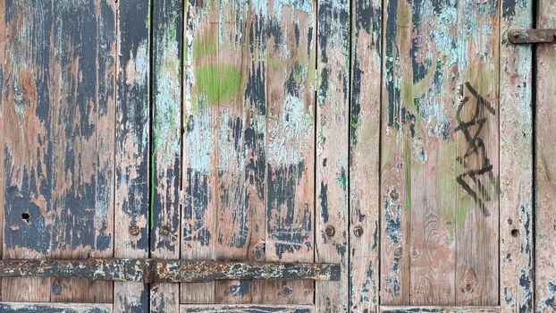 Close-up of a weathered wooden door showcasing intricate textures and peeling paint.