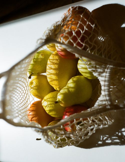 Free A vibrant assortment of apples and pears in a net bag casting playful shadows. Stock Photo