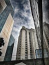 低角度拍摄的当代摩天大楼，玻璃外墙在多云的天空下