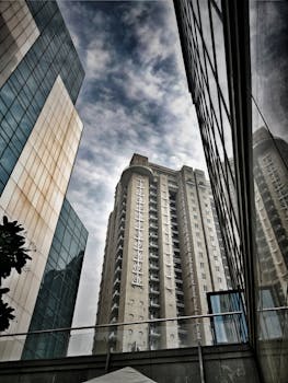 低角度拍摄的当代摩天大楼，玻璃外墙在多云的天空下