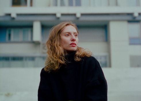 Redhead Woman with Long Wavy Hair Standing Before Residential Building