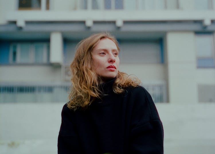 Redhead Woman With Long Wavy Hair Standing Before Residential Building