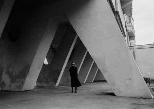 Free Woman in coat under modern building structure in black and white Moscow setting. Stock Photo