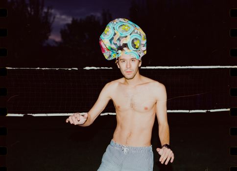 Man with Deflated Beach Ball on a Head at Night 