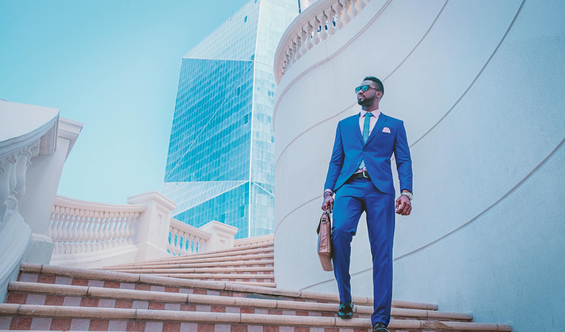 Stylish businessman walking up stairs with skyscraper backdrop in the UAE.