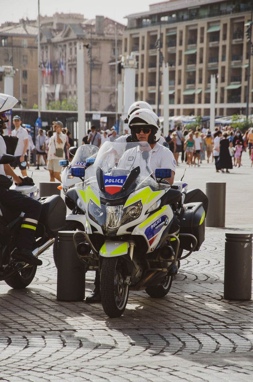 Politieagent op motorfiets die een drukke straat in een bruisende stad overdag patrouilleert.