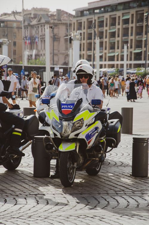 Free Policeman on motorbike patrolling crowded street in a bustling city during daytime. Stock Photo